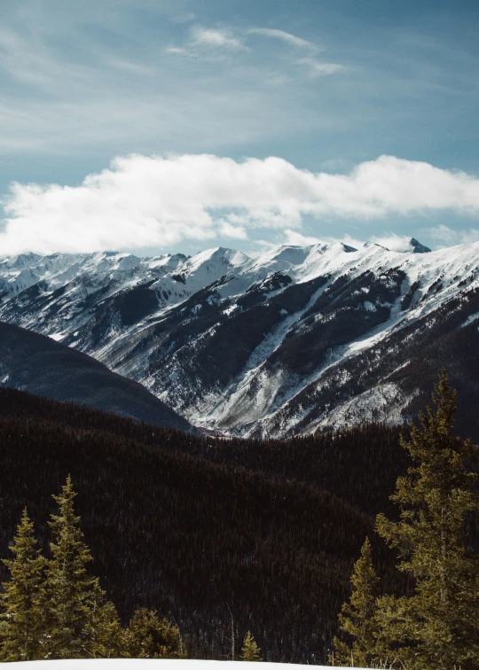 a ski slope with snow capped mountains and trees