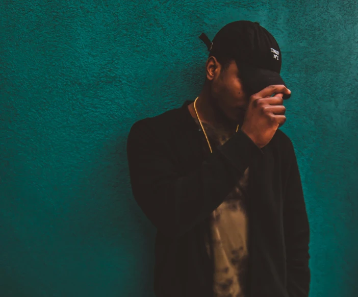 a person in a black hat with his hands together