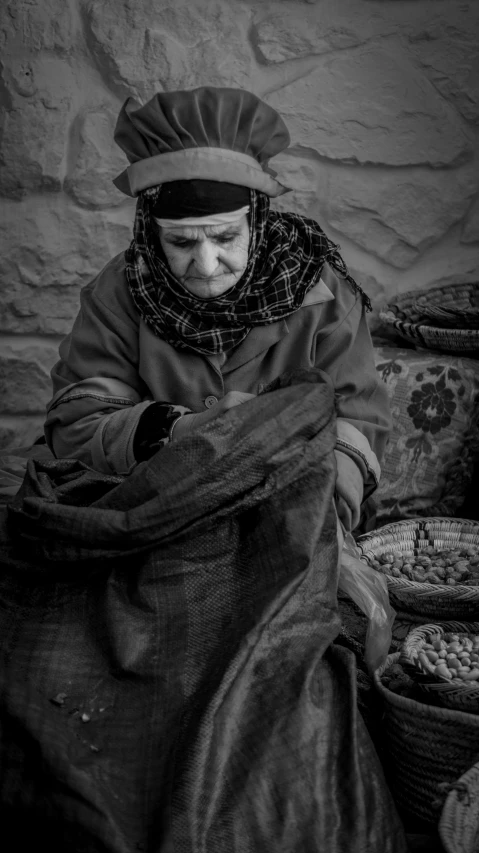 an older woman is sitting next to a wall with some baskets