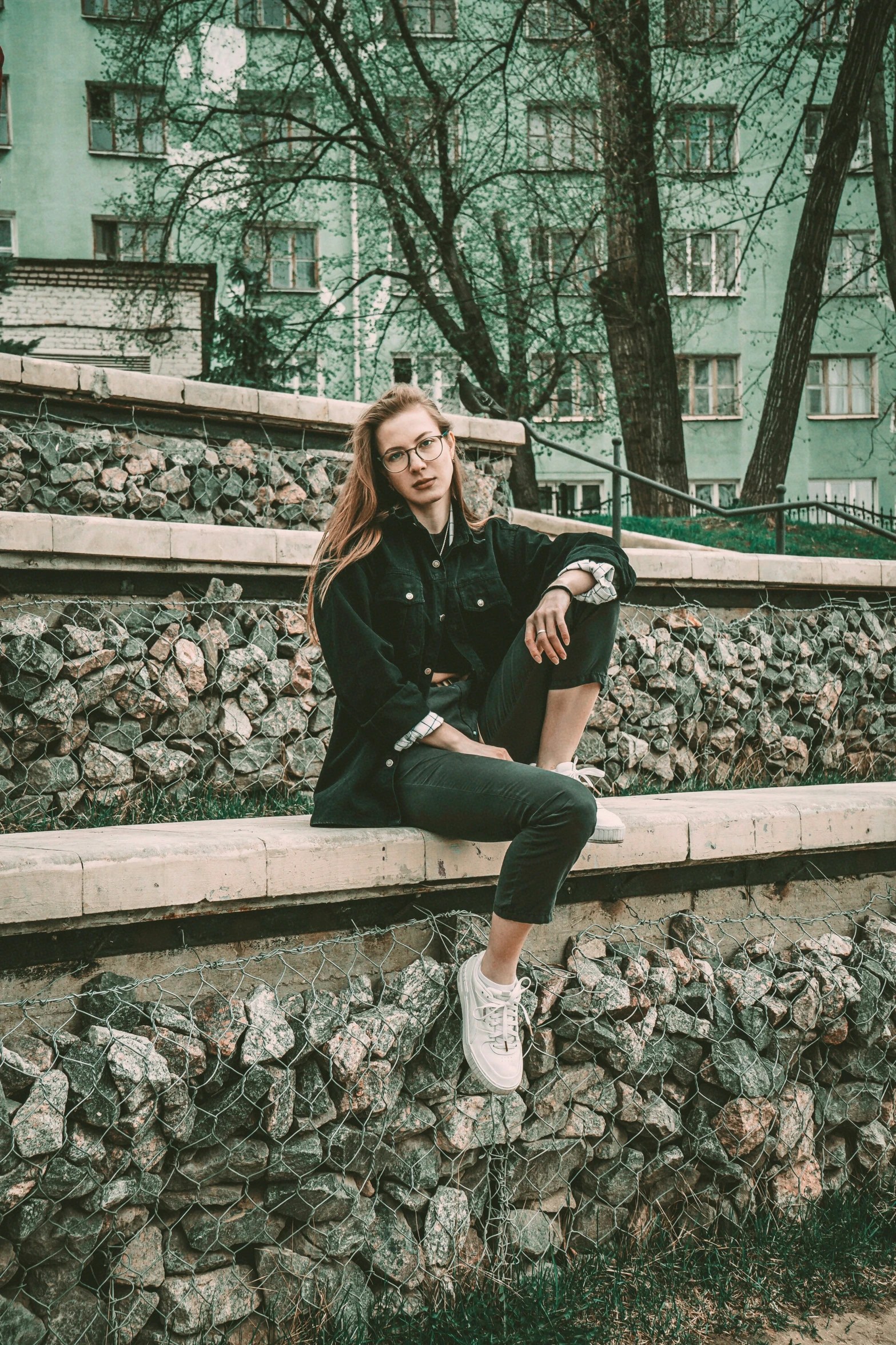 a woman is sitting on a stone wall