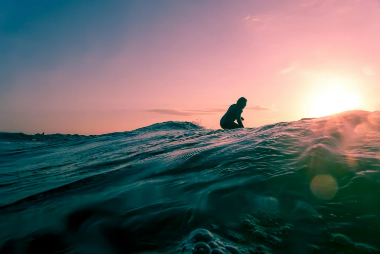 a silhouette of a man on a surfboard on top of a wave