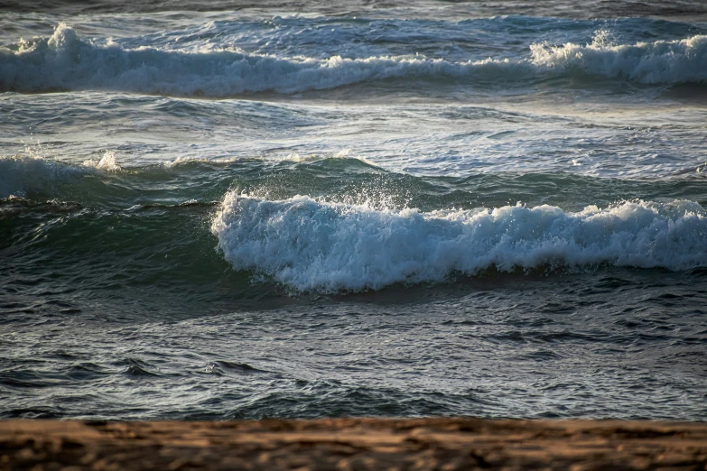 an ocean wave is hitting on the sand