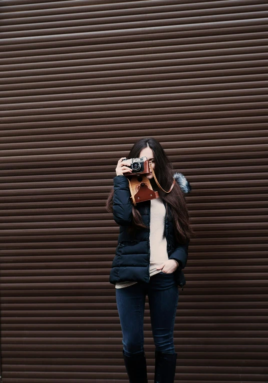 a woman wearing blue coat taking a po with her phone