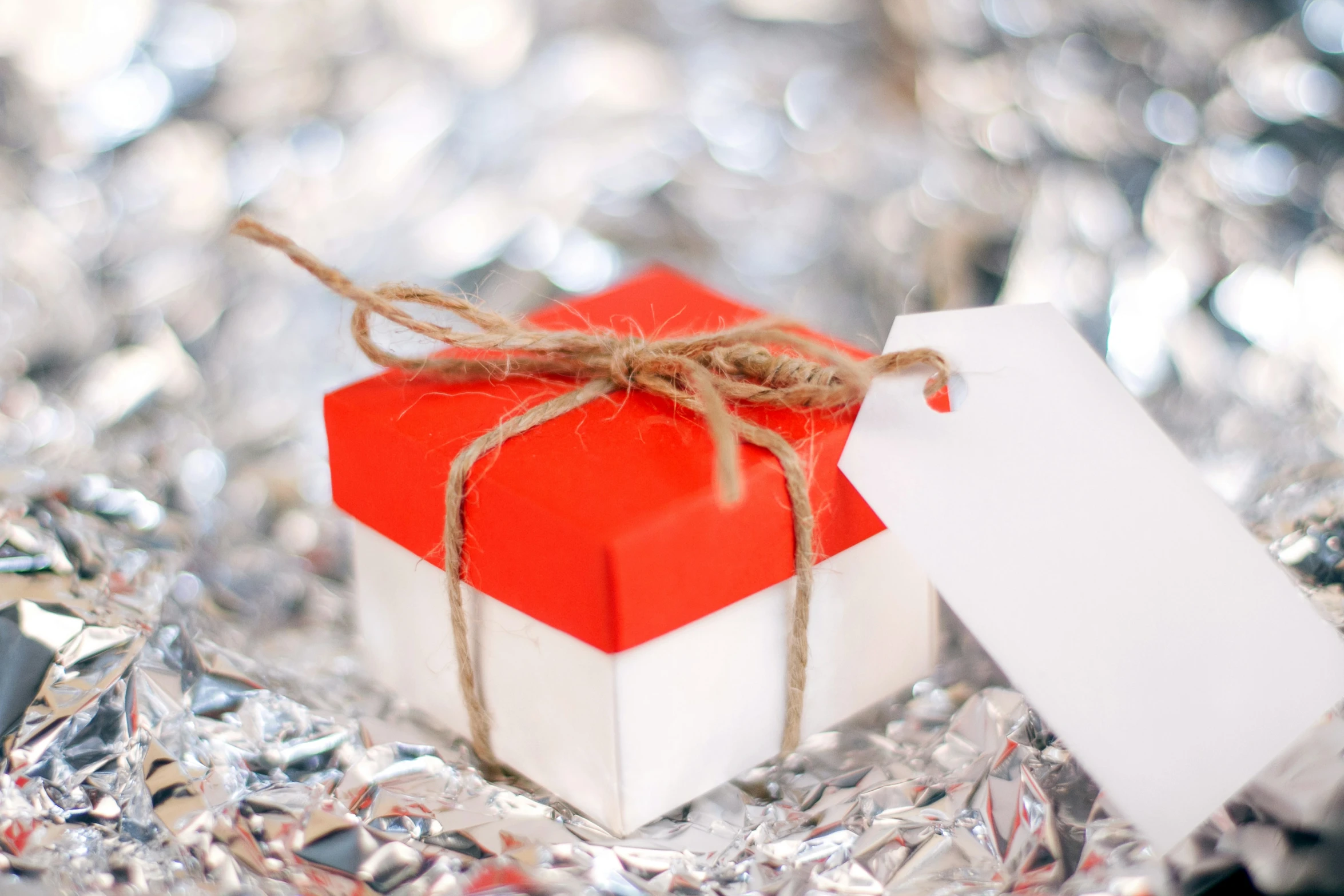 red gift box with white package tied with twine on shiny background