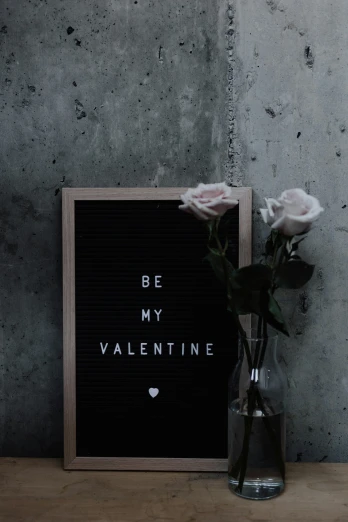 a vase with roses in it next to a black sign