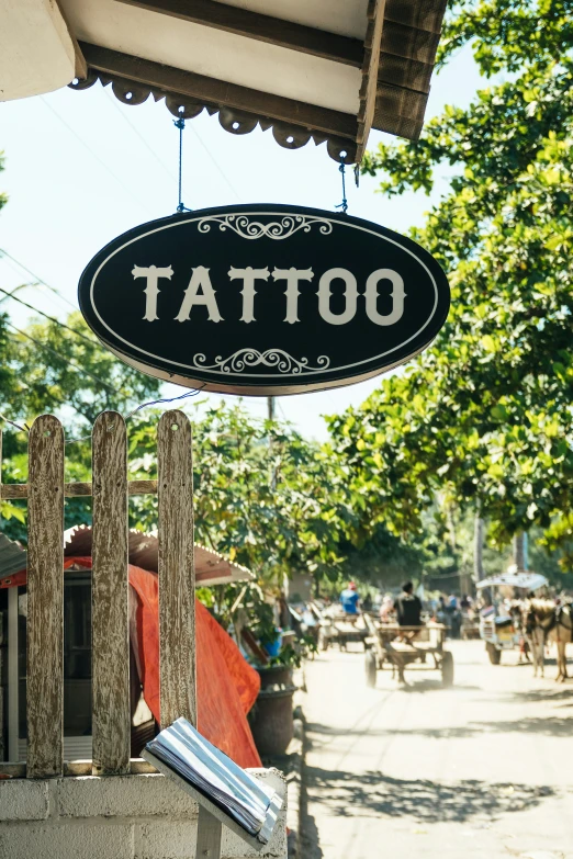 a sign hanging from a wooden fence above a street