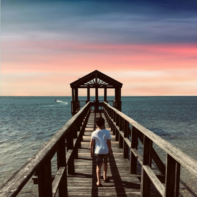 a couple walking on a pier during the sunset