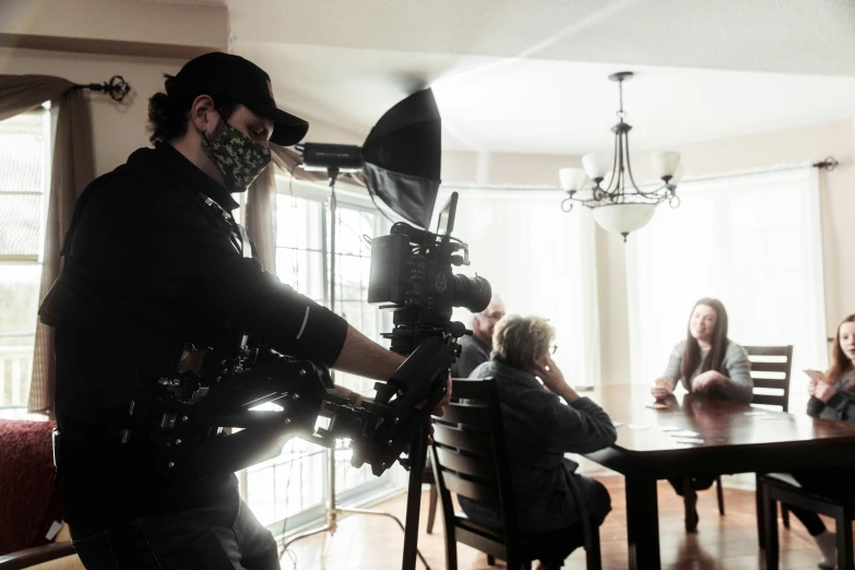 a man with cameras taking pictures of people sitting at the table