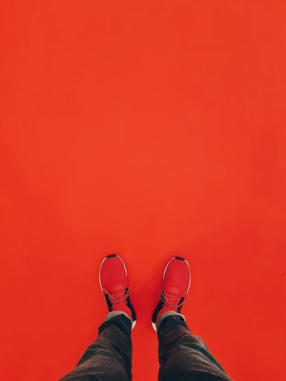 feet and shoes standing in front of a bright red wall