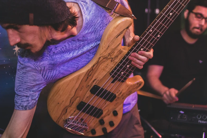 a young man with a guitar standing in front of another man