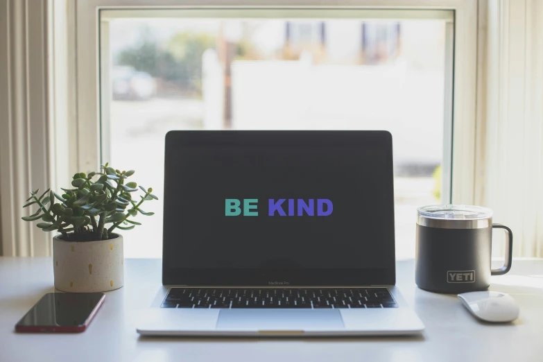 a laptop and a mouse with the words be kind on it