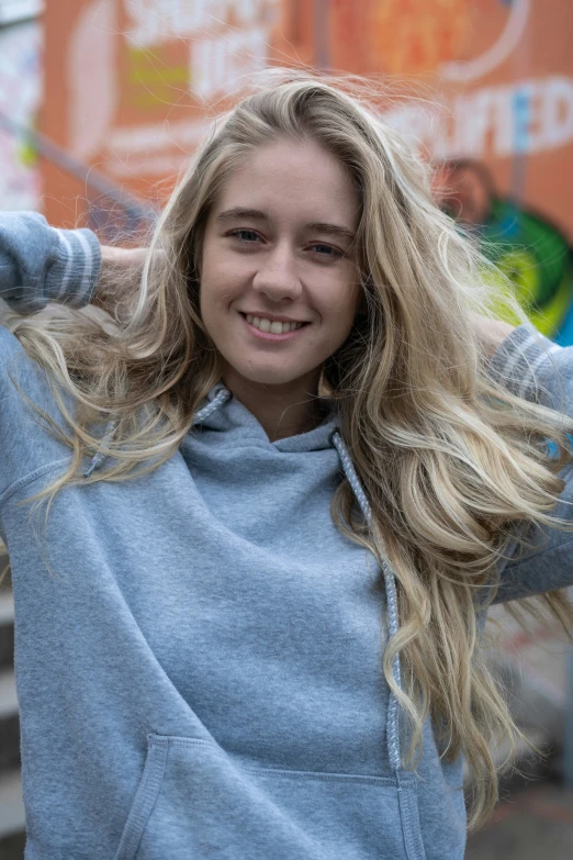 a girl in a blue hoodie is smiling for the camera