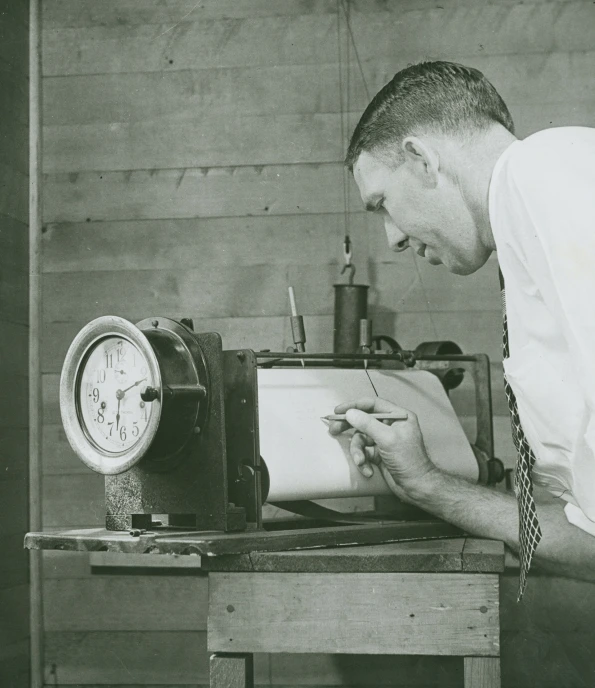 a man writing on a piece of paper next to an old clock