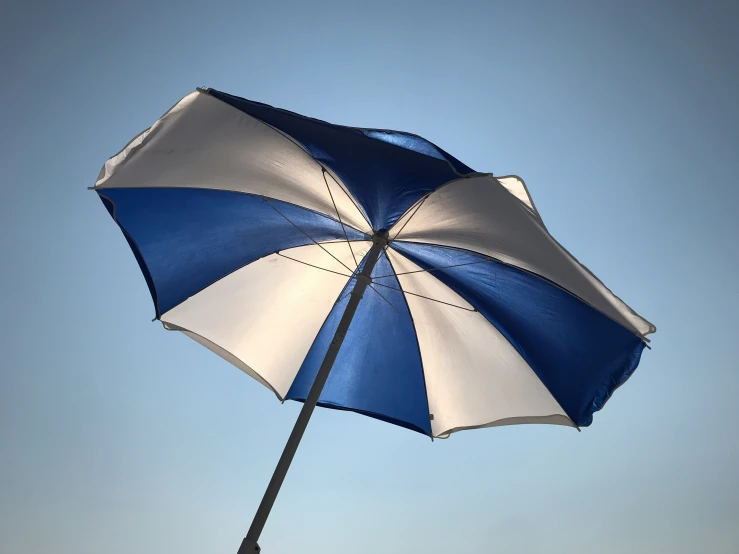 an umbrella is bent out against a blue sky