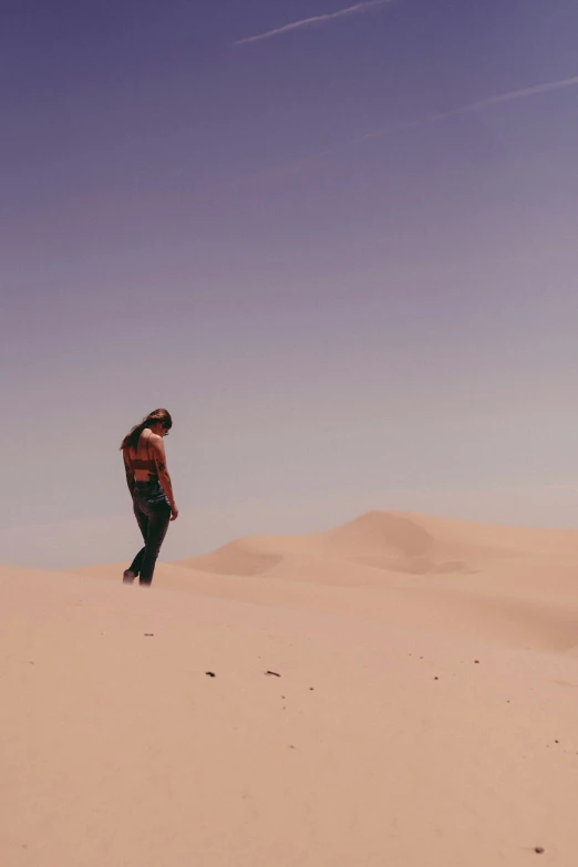 a woman standing on top of a desert near the sand