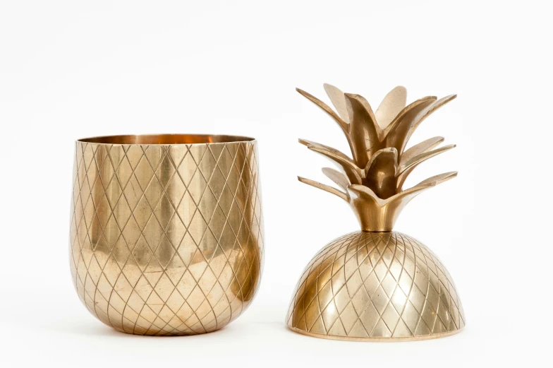 a golden vase sitting next to an elegant gold pineapple vase