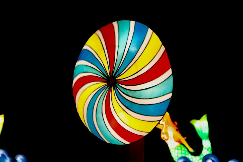 a very large colorful candy lollipop with a couple of people