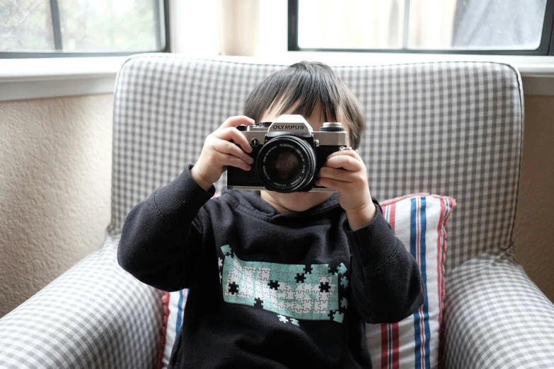 young child looking through a camera set up to take a po