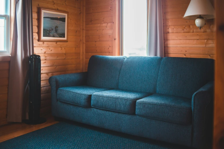 the living room has a couch and wooden paneled walls