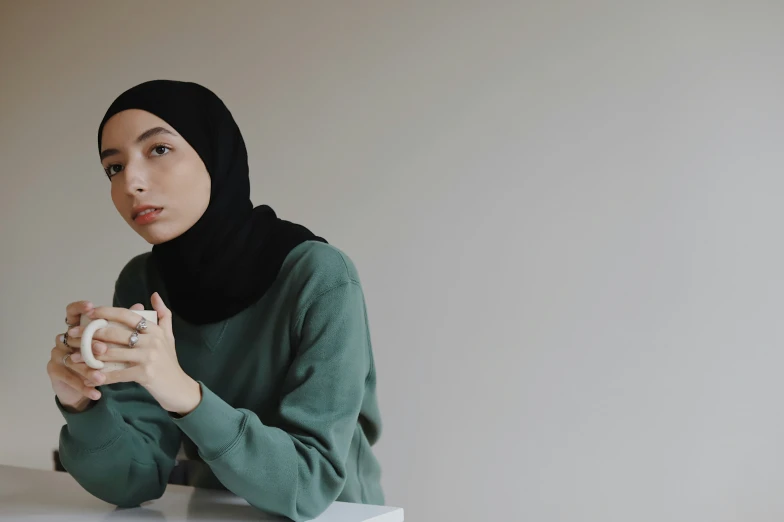 a woman in a green sweater holding a white object