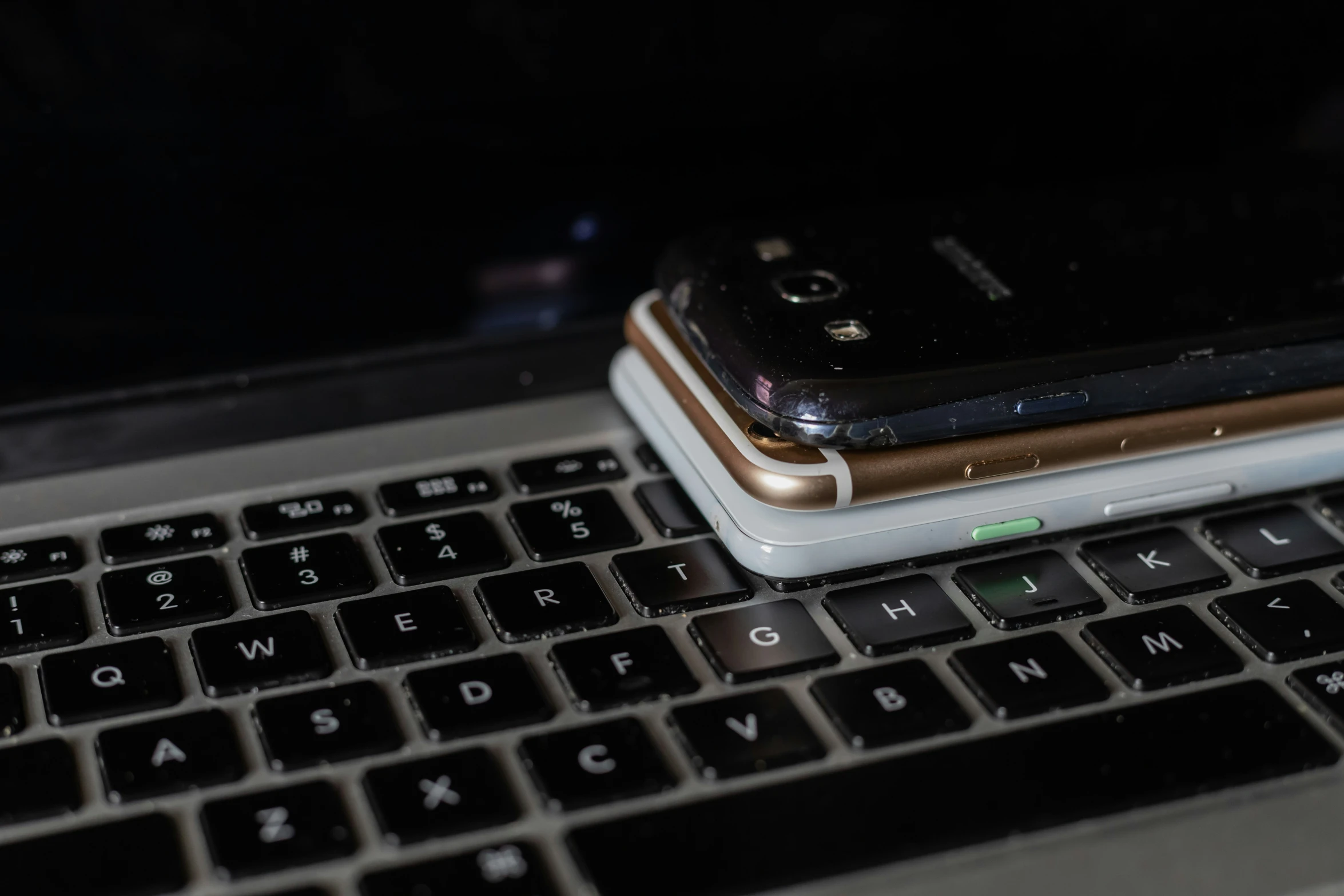 two cellphones are sitting on top of a keyboard