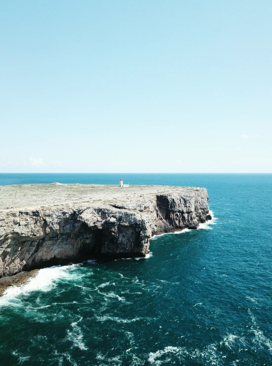 a person standing on the cliffs overlooking a beautiful ocean