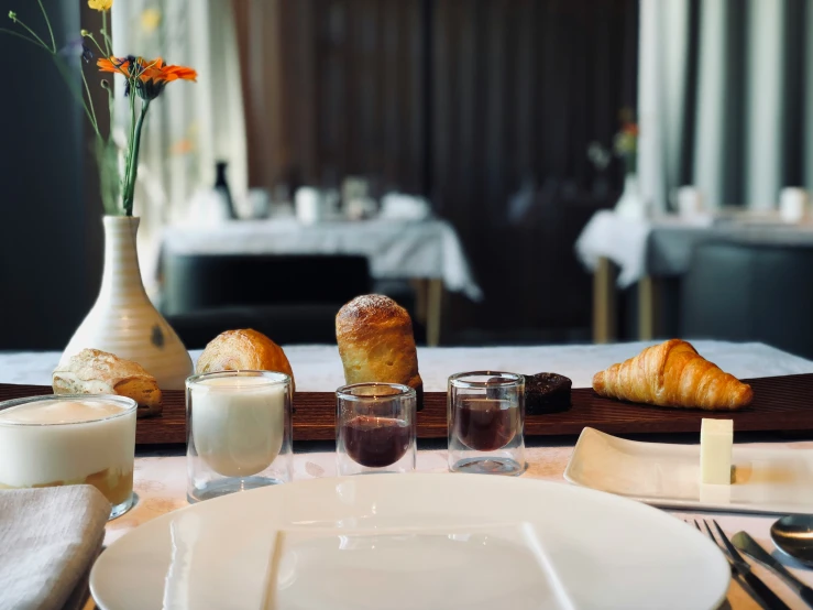 a table setting with glasses, croissants and wine