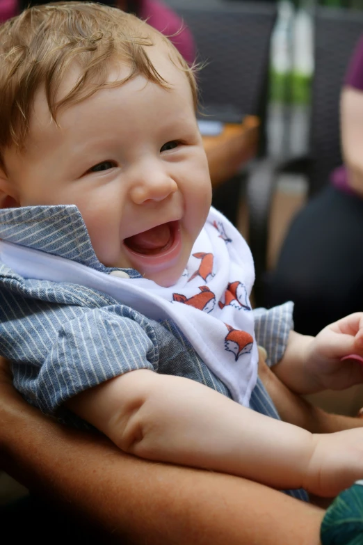 a baby smiles with his owner behind him