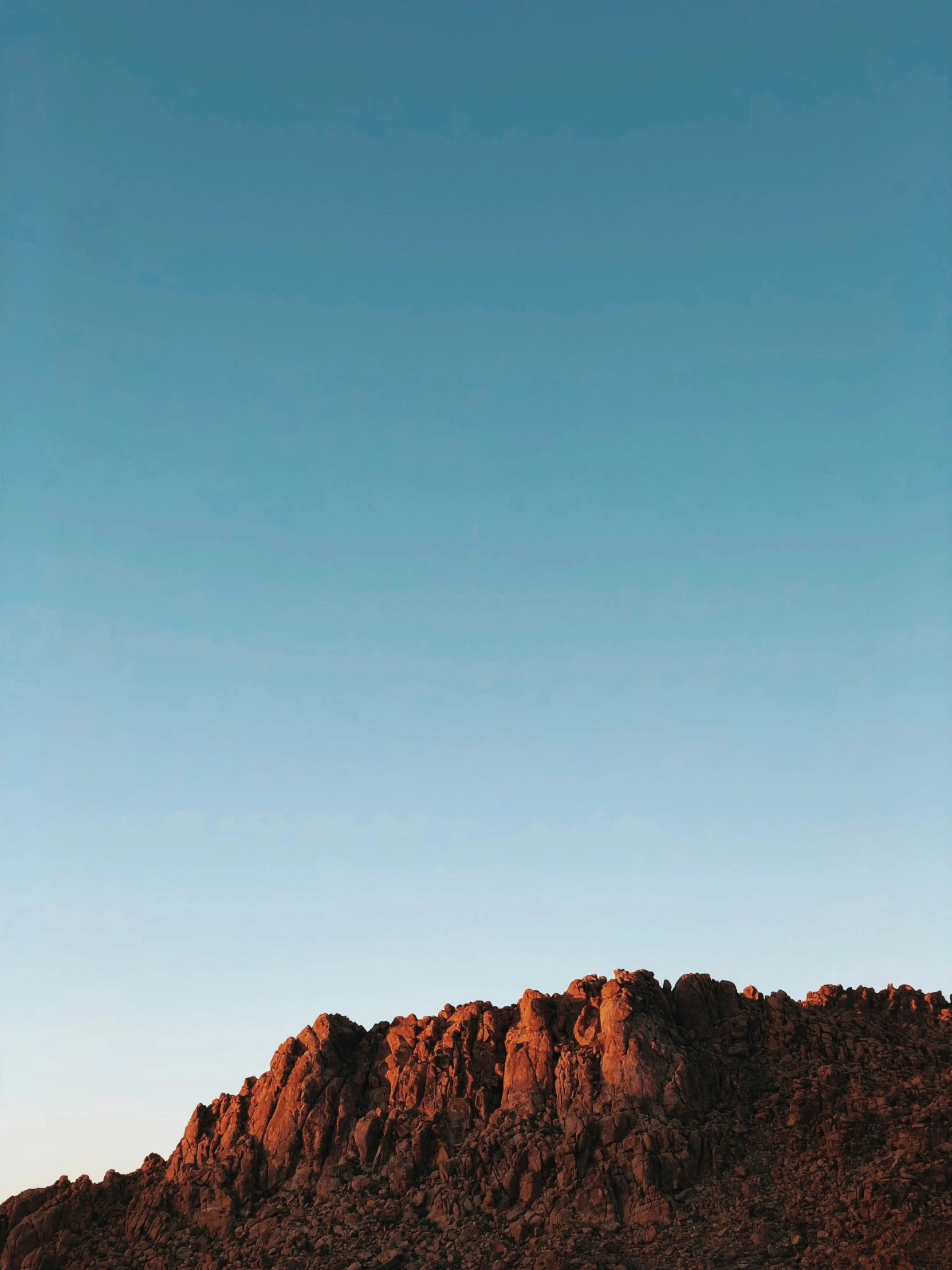 a lone plane flies above a large hill