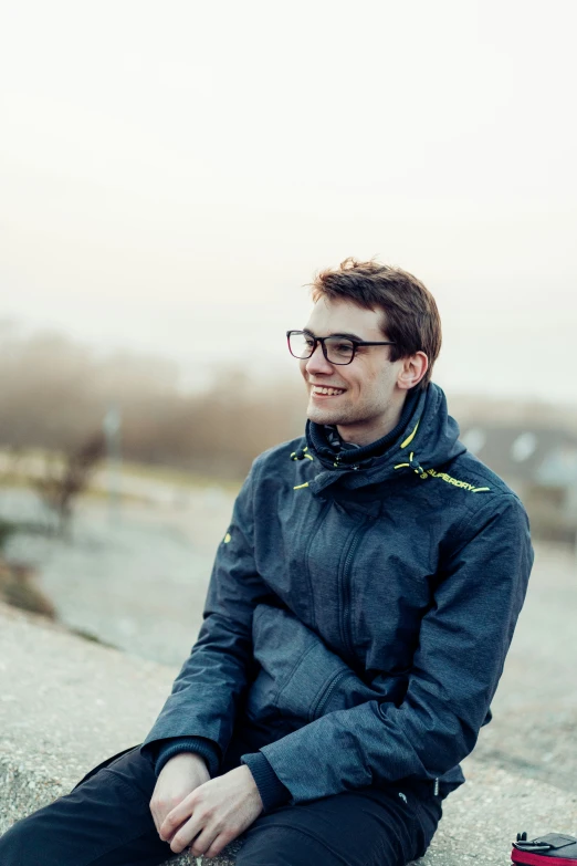 a man sitting on top of a sidewalk near a body of water