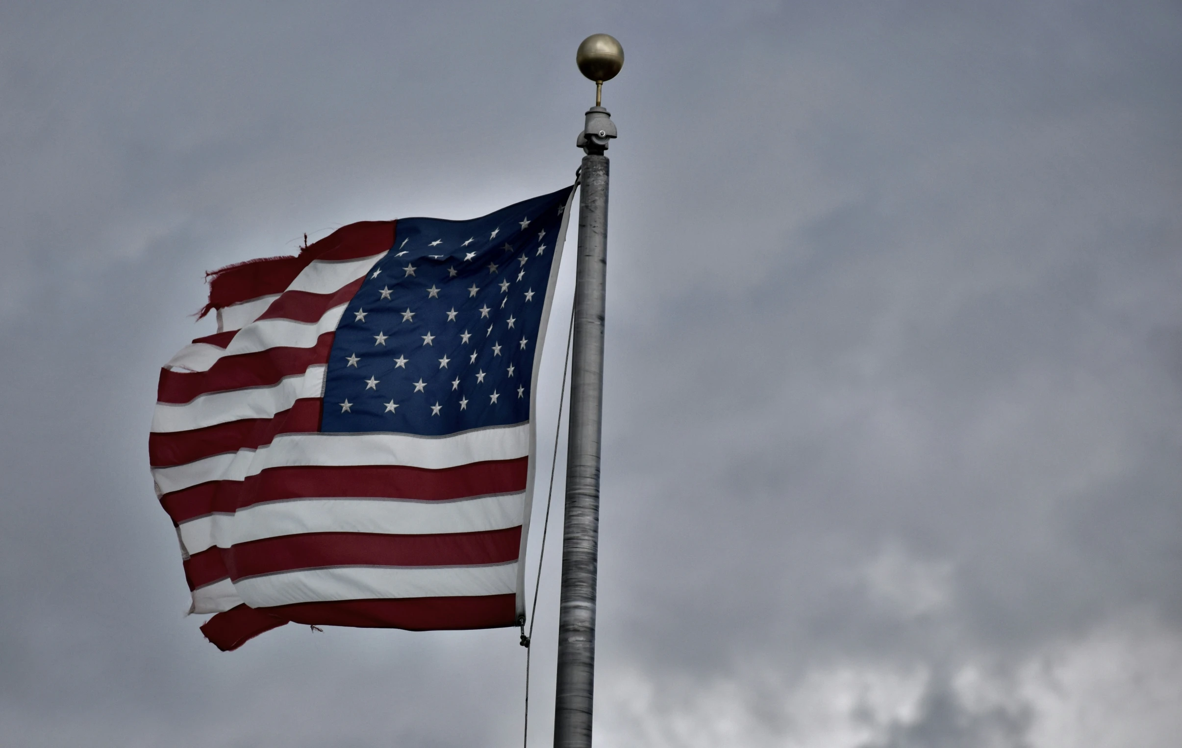 an american flag and a light pole against a cloudy sky