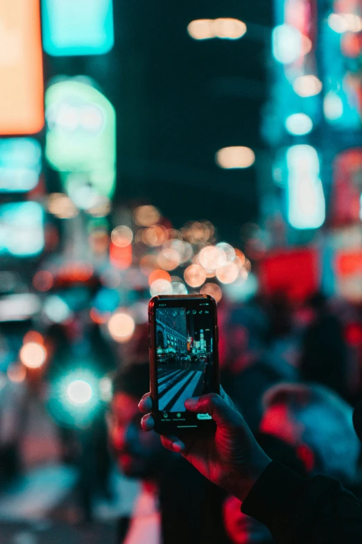 a person takes a picture with their phone at a busy city street