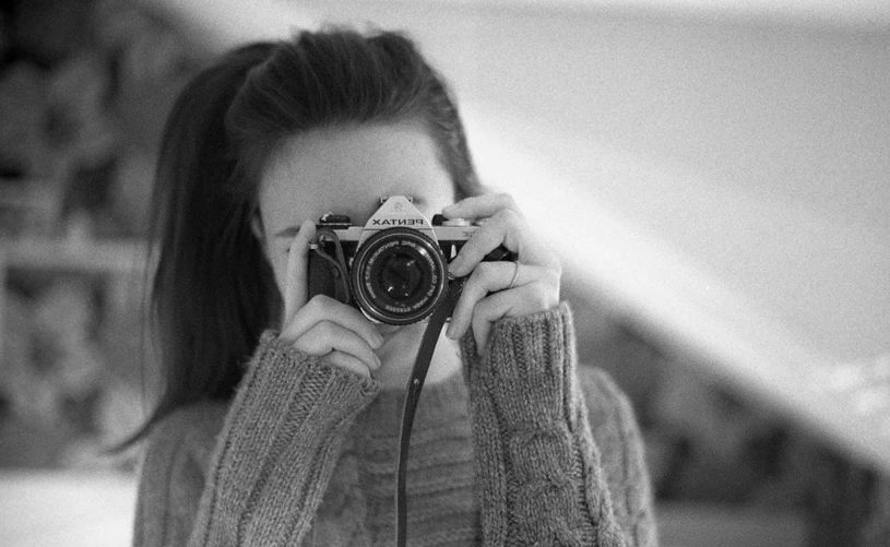 a woman in a sweater is holding a camera