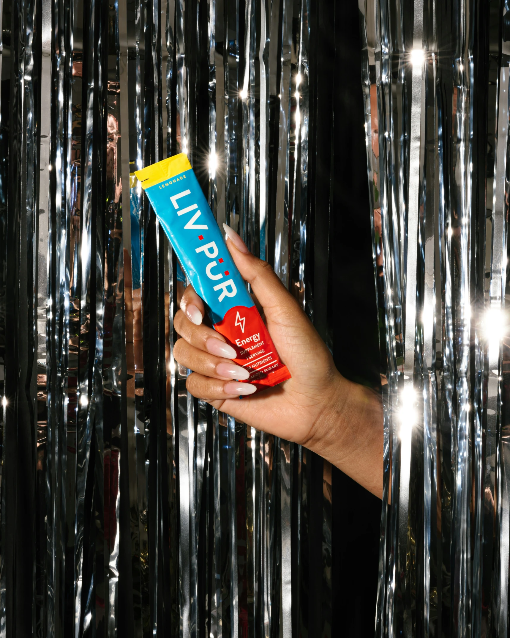 a woman holding up a tube of lip care in front of tinsely foil