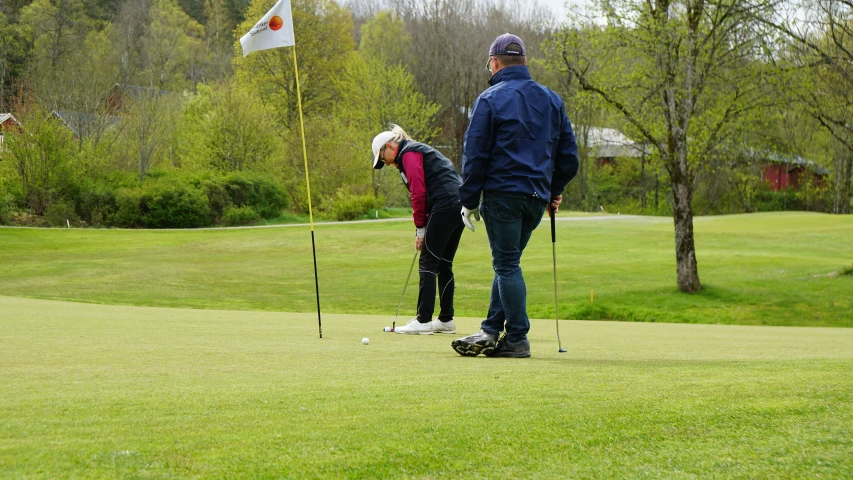 people standing on the grass putting putts in a golf hole