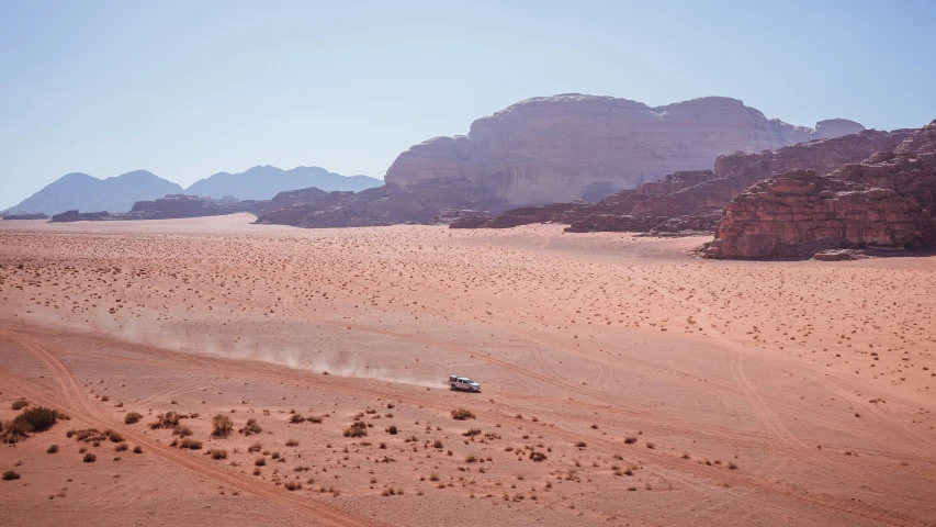 some mountains and sand some rocks and a car