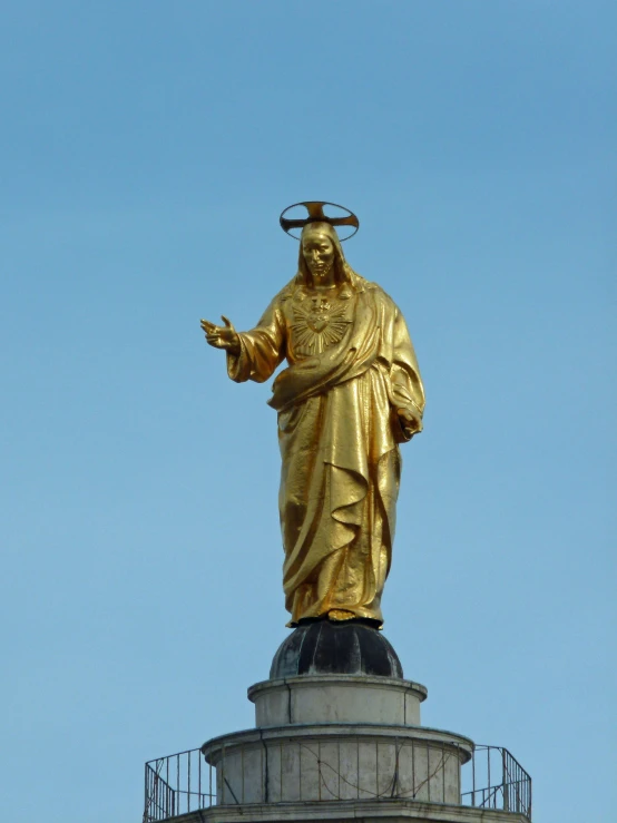 statue of a saint in gold on top of a stone structure