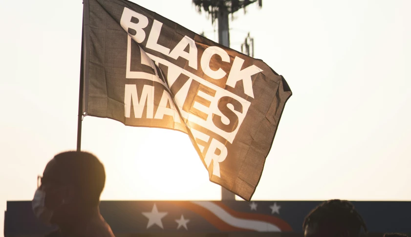 some people are sitting near a big black flag