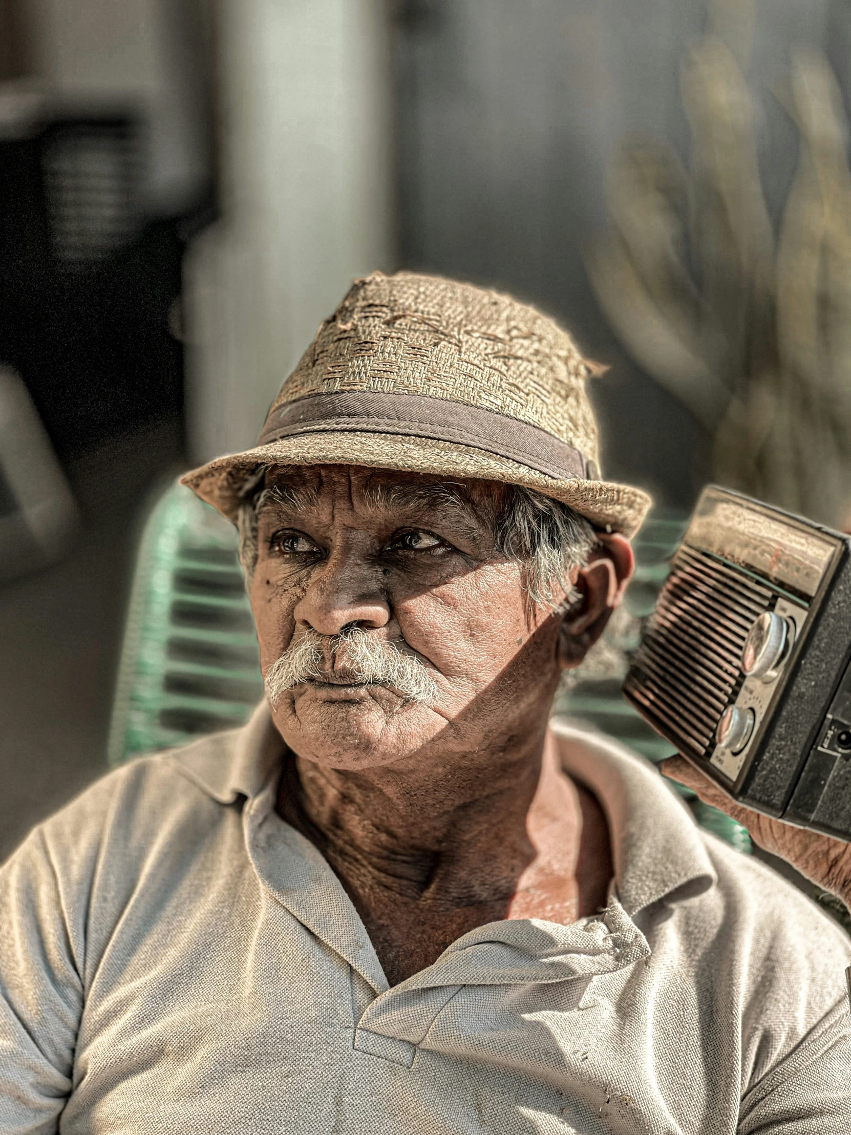 an older man sitting on a couch and holding a small old fashioned radio