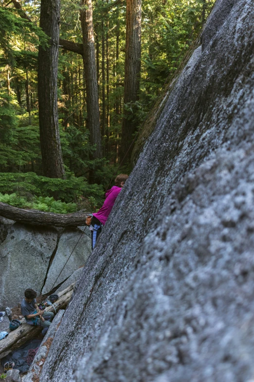 two people are climbing on rocks in the woods