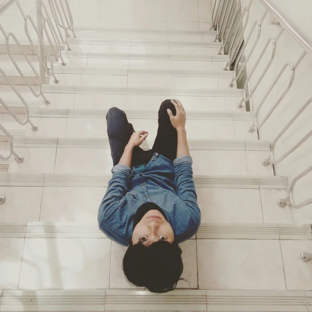 the man is laying on the floor under some stairs