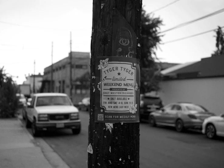 a wooden pole with a sign on it on a city street