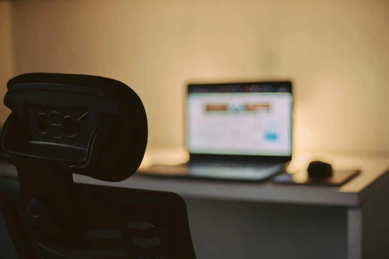 a laptop computer is on a desk near a chair