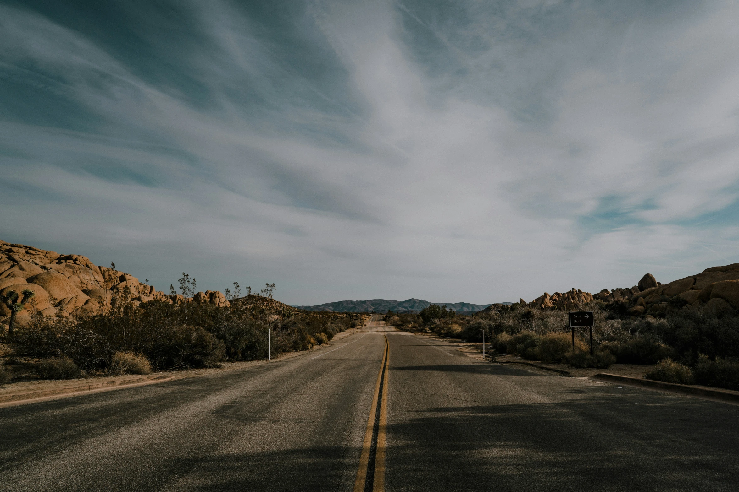 a deserted road is pictured with a blue sky and clouds