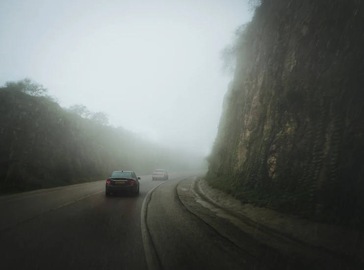 foggy mountain road in front of a car traveling through it