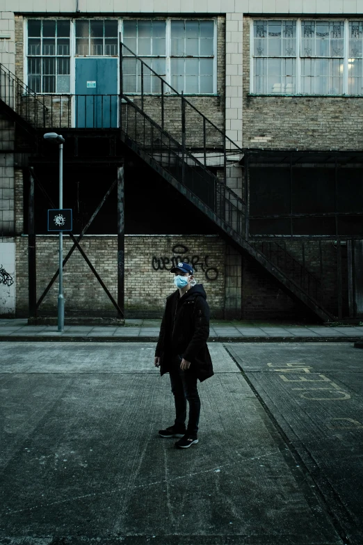 a man wearing a mask standing in the middle of an open empty parking lot