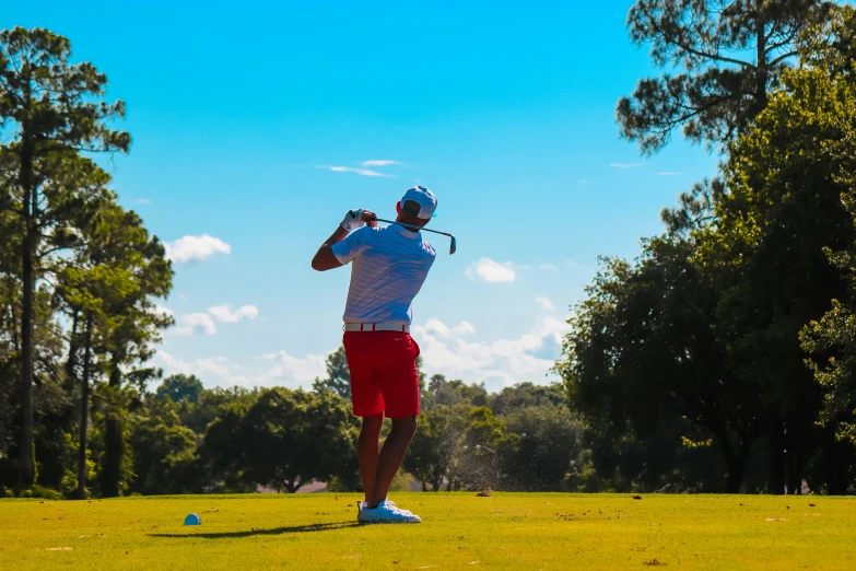 a man in red shorts is standing in the grass