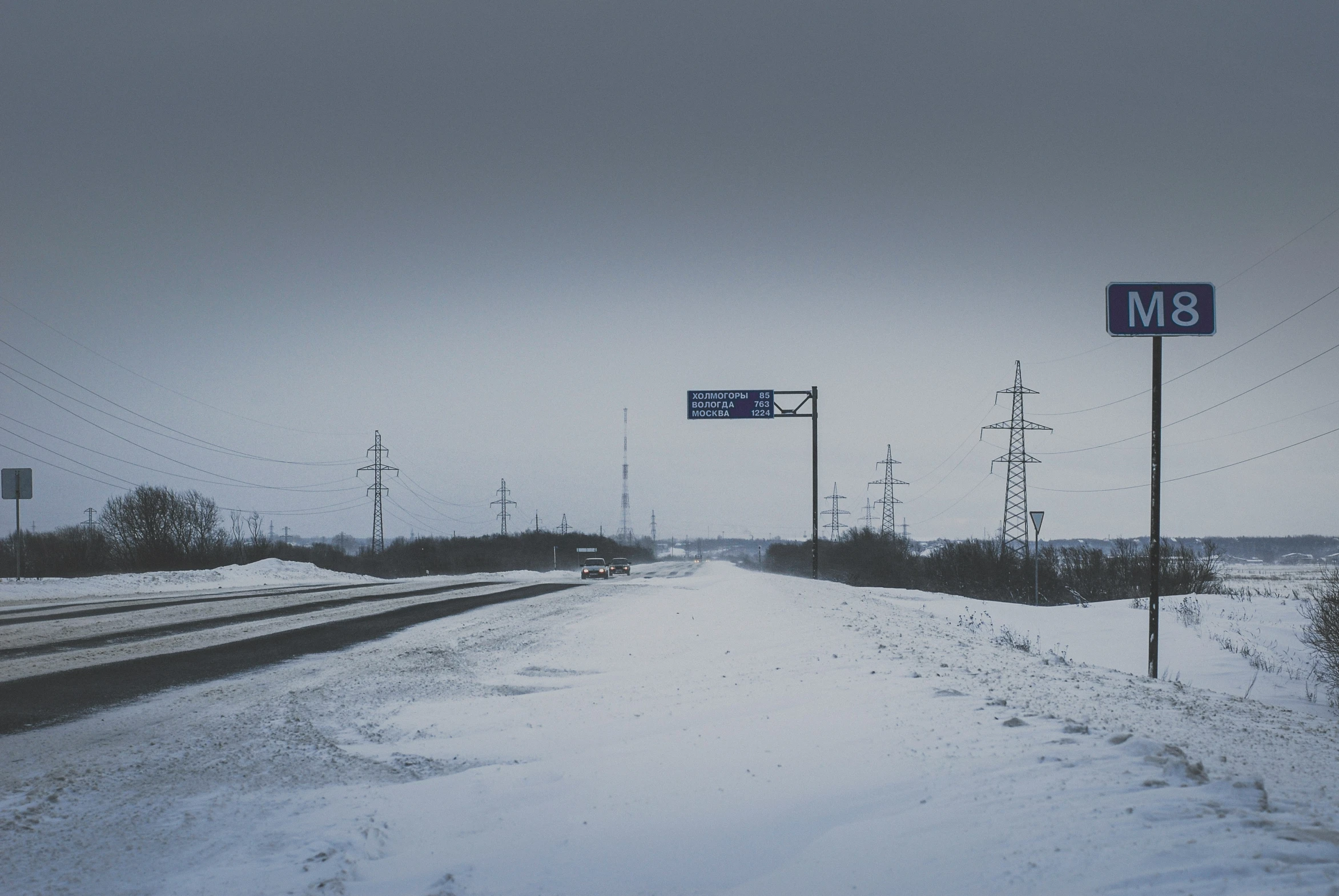 the highway on a snowy day with a street sign on it