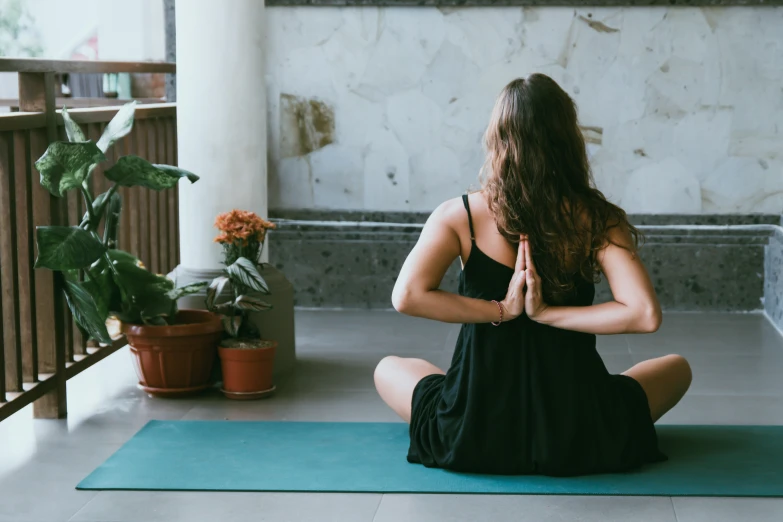 a woman practices yoga in front of some plants