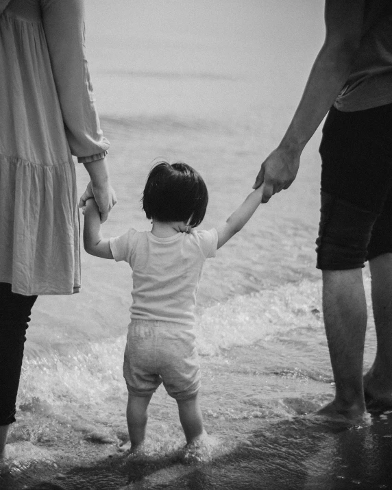 an image of a man and woman holding the hands of a young child